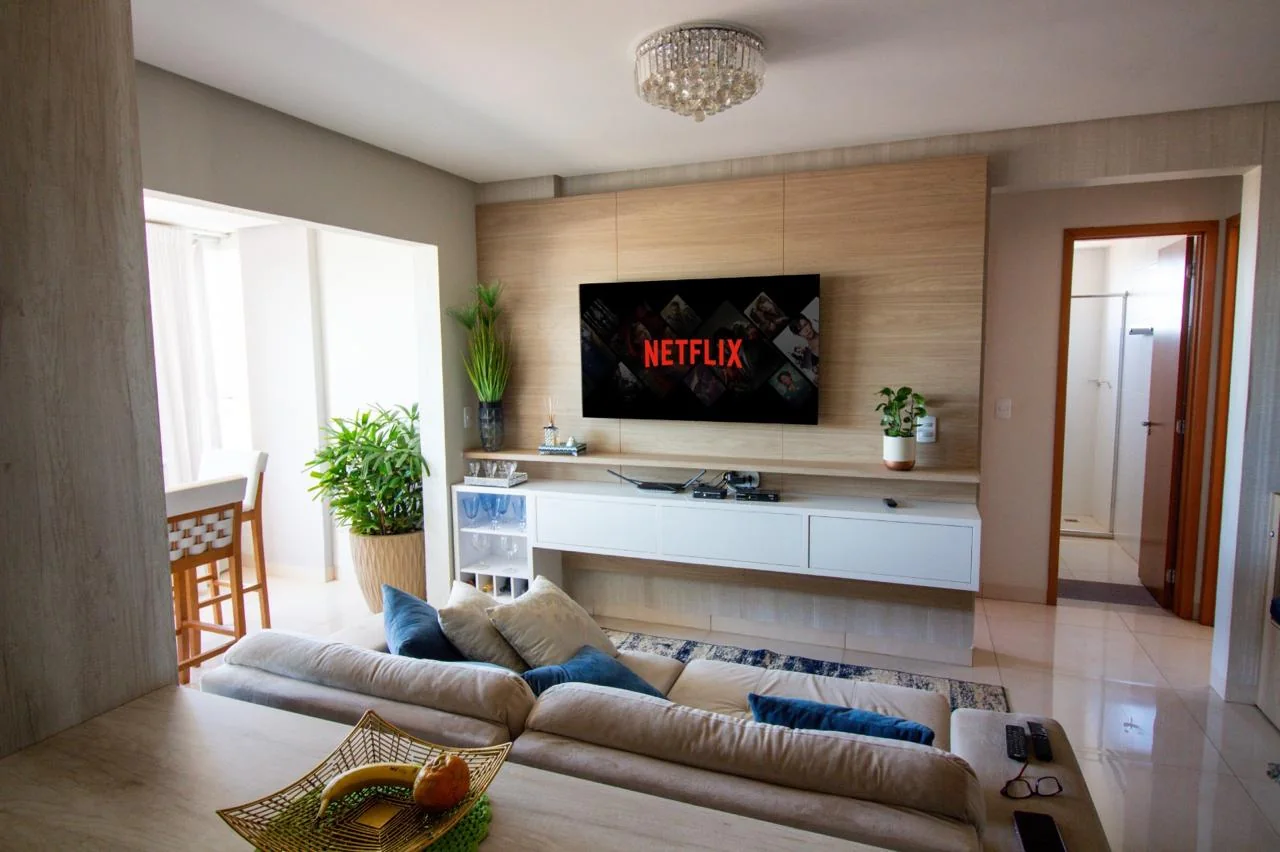 Sala de estar com painel amadeirado e rack branco suspenso